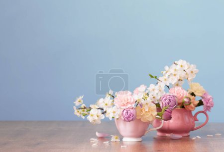 Photo for Beautiful spring flowers in two cups in pastel colors on blue background - Royalty Free Image