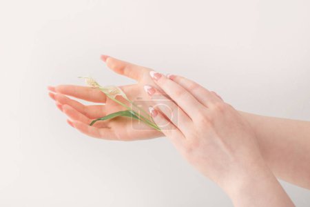 Téléchargez les photos : Mains féminines avec de beaux ongles longs avec des fleurs sur fond blanc - en image libre de droit