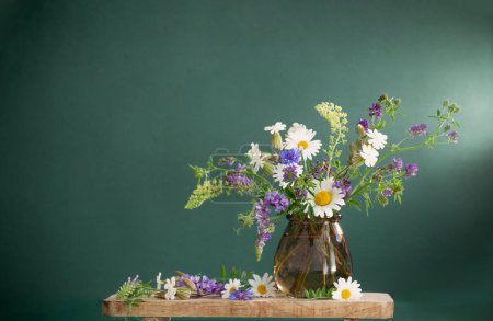 Foto de Flores silvestres en jarrón de cristal marrón sobre fondo verde - Imagen libre de derechos