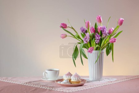 Photo for Cup of tea and cupcakes with spring flowers in light colors - Royalty Free Image