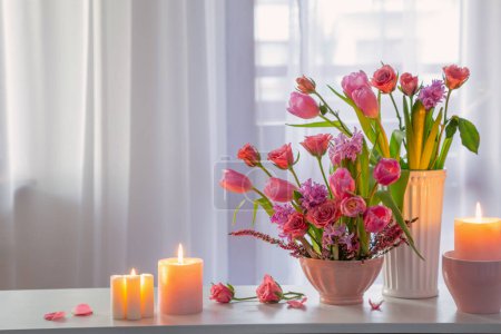 Photo for Spring flowers with burning candles on background window - Royalty Free Image