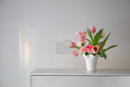 Photo for Pink spring flowers in white ceramic vase in modern home interior - Royalty Free Image