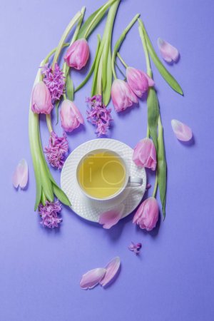 Photo for Green tea with spring flowers on purple background - Royalty Free Image