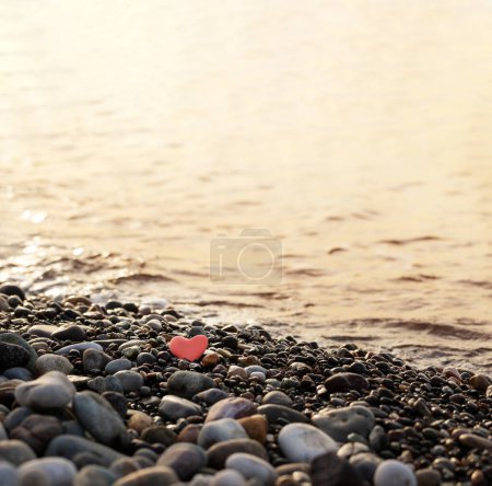 Téléchargez les photos : Pierre rouge en forme de coeur sur la plage par la mer - en image libre de droit