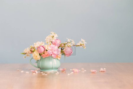 Foto de Hermosas flores de primavera en copa vintage en colores pastel sobre fondo azul - Imagen libre de derechos