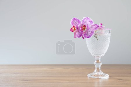 Foto de Orquídea púrpura en vidrio sobre mesa de madera - Imagen libre de derechos