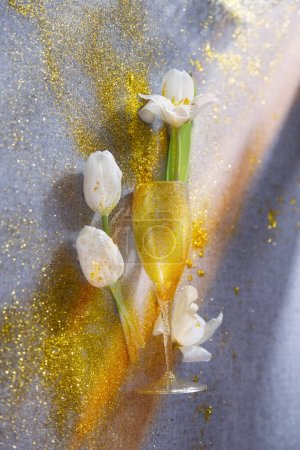 Téléchargez les photos : Tulipes blanches avec verre doré sur la table - en image libre de droit