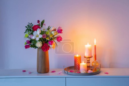 Photo for Flowers  in vase and burning candles on shelf  on background wall - Royalty Free Image