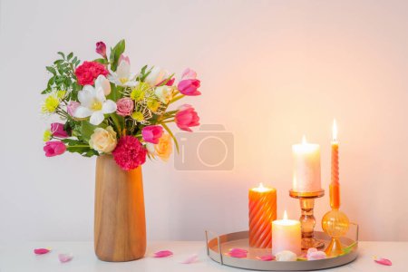 Photo for Flowers  in vase and burning candles on shelf  on background wall - Royalty Free Image