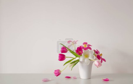 Téléchargez les photos : Tulipes blanches et roses dans un vase blanc sur le mur de fond - en image libre de droit