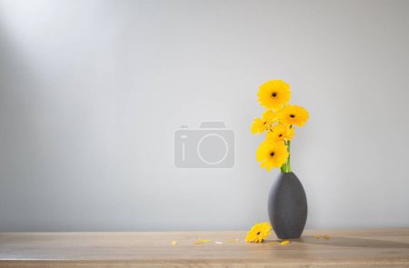 Téléchargez les photos : Gerbera jaune dans un vase sur une étagère en bois - en image libre de droit