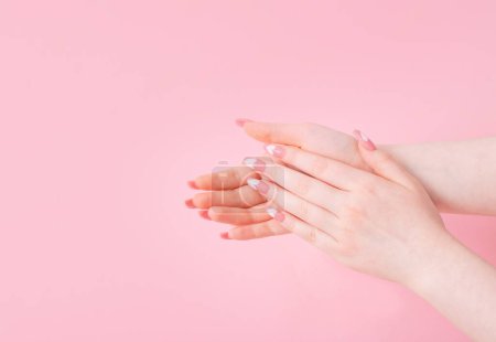 Téléchargez les photos : Mains féminines avec de beaux ongles longs avec manucure avec motif coeur sur fond rose - en image libre de droit