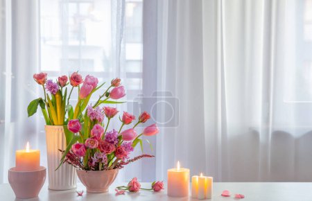 Foto de Flores de primavera con velas encendidas en la ventana de fondo - Imagen libre de derechos