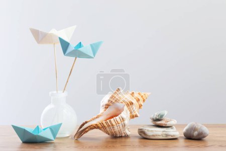 Téléchargez les photos : Bateaux en papier dans un vase en verre avec décor marin sur une table en bois - en image libre de droit
