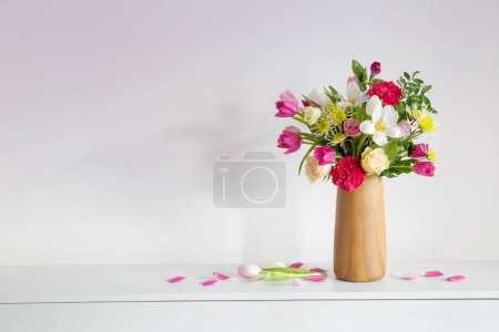 Photo for Beautiful flowers  in vase on shelf  on background white wall - Royalty Free Image