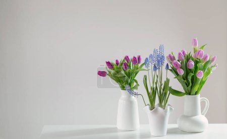Foto de Flores de primavera en jarrones blancos en el interior blanco - Imagen libre de derechos