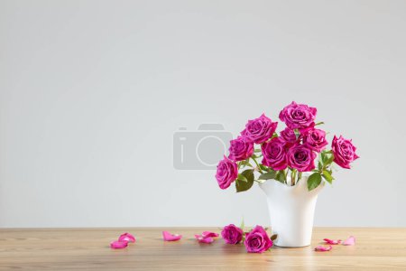 Téléchargez les photos : Roses violettes dans un vase sur fond blanc - en image libre de droit