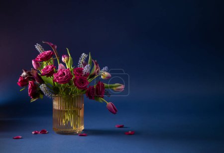Téléchargez les photos : Belles fleurs dans un vase en verre sur fond bleu - en image libre de droit