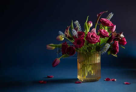 Téléchargez les photos : Belles fleurs dans un vase en verre sur fond bleu - en image libre de droit