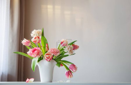 Foto de Flores de primavera rosa en jarrón de cerámica blanca en el interior del hogar moderno - Imagen libre de derechos