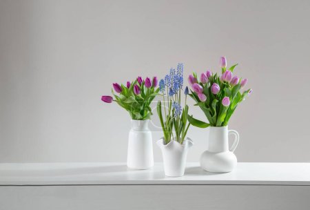 Frühlingsblumen in weißen Vasen im weißen Inneren