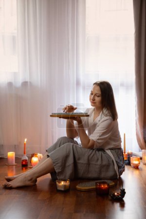 Foto de Mujer joven interior con tablero de uñas y velas encendidas - Imagen libre de derechos
