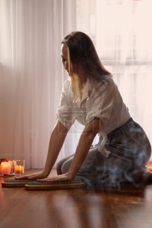 Téléchargez les photos : Jeune femme intérieure avec planche à ongles et bougies allumées - en image libre de droit