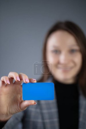 Foto de Feliz mujer de negocios colding tarjeta de papel azul en la mano - Imagen libre de derechos