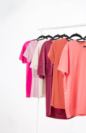Reihe von T-Shirts auf einem Kleiderbügel vor dem Hintergrund eines weißen Wandhängers