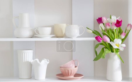 Photo for Tulips in vase on white shelf with kitchenware - Royalty Free Image