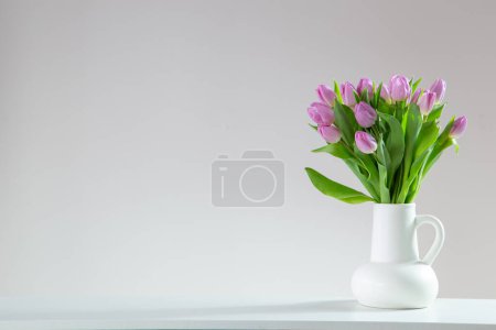 Foto de Tulipanes rosados en jarra blanca sobre fondo blanco - Imagen libre de derechos