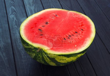 Photo for Sliced half of watermelon on black wooden background. Red ripe autumn season fruit or vegetable. - Royalty Free Image