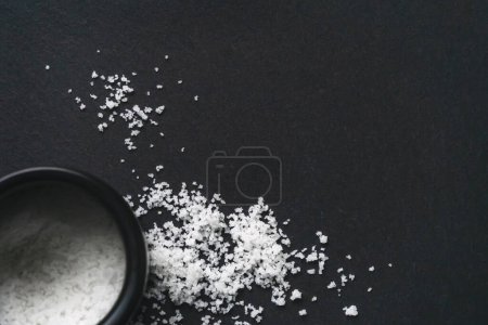 Organic sea white salt and a jar on a black slate stone background. Concept of cooking natural healthy food. Copy space. 