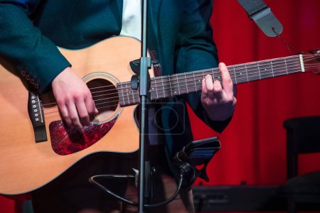 Foto de El hombre toca la guitarra clásica contra cortina roja - Imagen libre de derechos