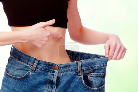 Frau zeigt, wie viel Gewicht sie verloren hat, Mädchen zeigt ihre alte riesige Jeans