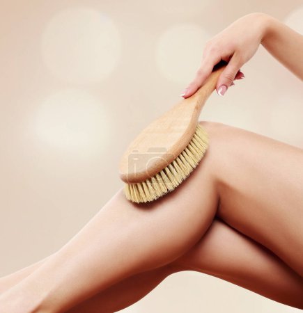 Téléchargez les photos : Femme massant sa jambe à l'aide d'une brosse - en image libre de droit