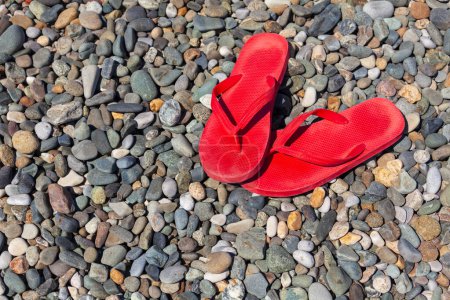 Téléchargez les photos : Tongs rouges sur une plage de galets - en image libre de droit