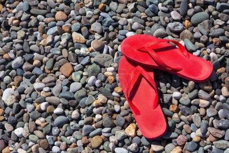 Photo for Red flip flops on a pebble beach. - Royalty Free Image