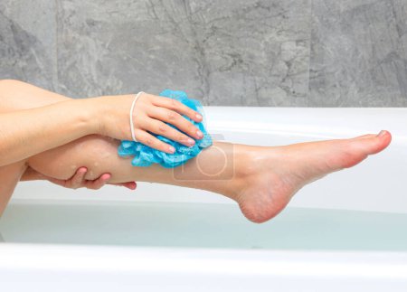 Téléchargez les photos : Femme lavant son corps dans le bain. Gros plan des jambes féminines dans une baignoire - en image libre de droit