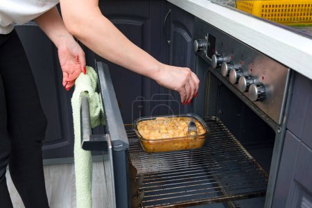 Photo for Close up of a woman's hands cooking a pie in the oven. - Royalty Free Image