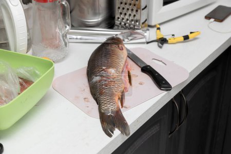 Foto de Carpa de pescado y cuchillo en una mesa de cocina - Imagen libre de derechos