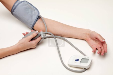 Téléchargez les photos : Mesure de la pression artérielle. Mains de femme avec tonomètre sur fond blanc. - en image libre de droit
