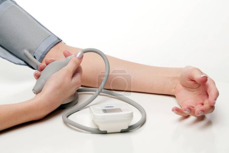 Téléchargez les photos : Blood pressure measurement. Woman hands with tonometer on white background. - en image libre de droit