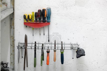 Foto de Destornilladores y otras herramientas colgadas en una pared en un taller - Imagen libre de derechos