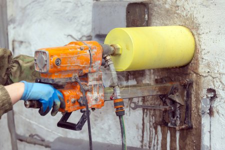 Photo for Worker using an electric drill to make a hole in a concrete wall, closeup - Royalty Free Image