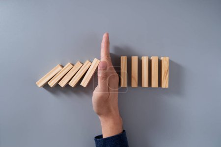 Photo for Male hand blocking dominos from topping over - Royalty Free Image