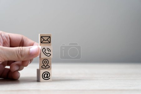 Photo for Contact us, hand of businessman points to the wood cubes with mail, phone, internet and location icons, cutomer support or service concept - Royalty Free Image