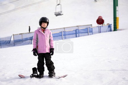 Téléchargez les photos : Action motion photo d'une enfant asiatique snowboarder sur la piste de ski de montagne faisant style snowboard gratuit. - en image libre de droit