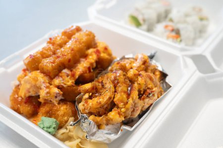 Téléchargez les photos : Rouleau de sushi aux crevettes brûlées avec mayonnaise épicée et sauce teriyaki dans un récipient à emporter - en image libre de droit