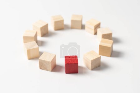Téléchargez les photos : Un seul bloc de bois rouge unique disposé parmi d'autres blocs de cube en bois en cercle rond, concept de unique, différent, diversité, exceptionnel, remarquable ou talent - en image libre de droit